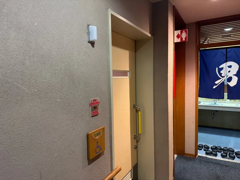 車椅子マークと緊急呼び出しボタンがある多目的トイレの引き戸
